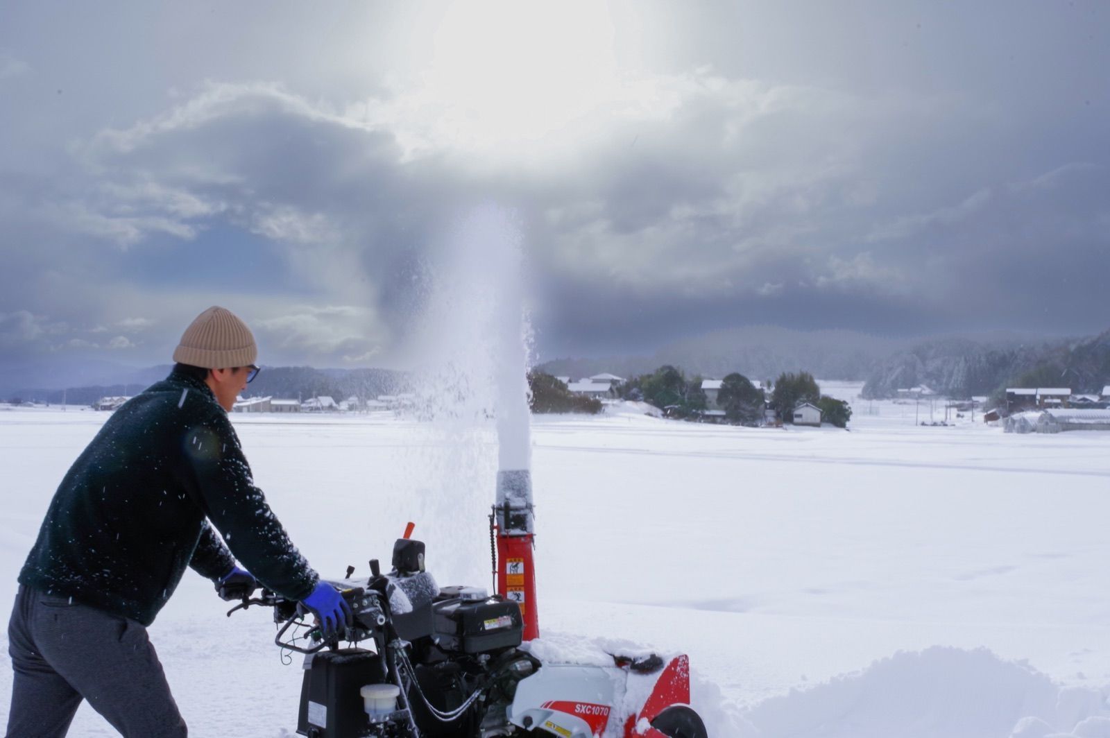 雪を飛ばしながら除雪機を操作する様子(イメージ写真)